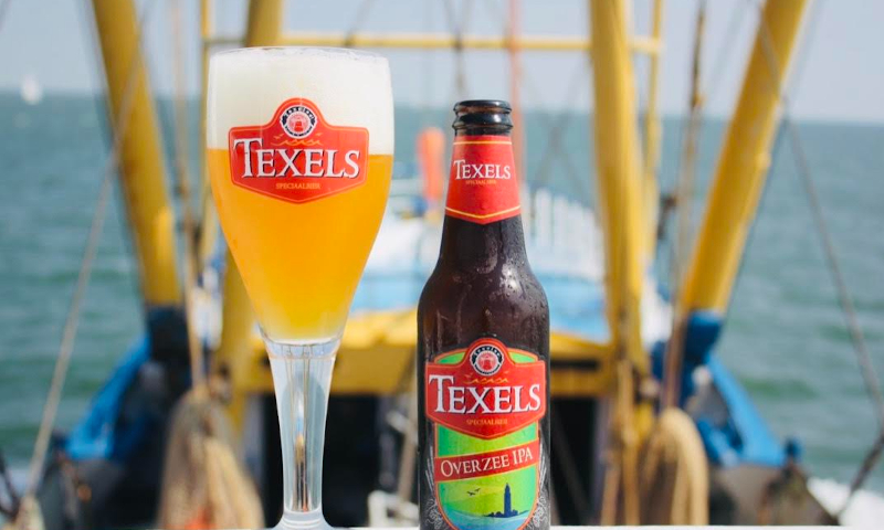 Texels Overzee IPA gevuld glas en het flesje ernaast op een boot